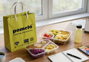 Lime green Pomeló catering bag on a desk beside three clear meal-prep containers with vegetables and pasta, and a bottle of juice by a calendar and phone.