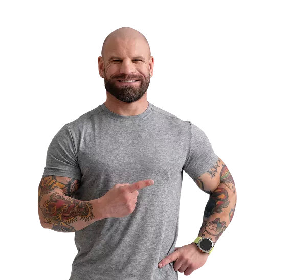 Smiling tattooed man in a gray t-shirt pointing at himself with his right finger.